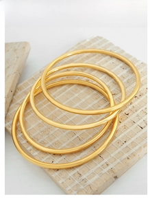 Set di quattro bracciali rigidi minimalisti in acciaio al titanio dorato lucido su pietra