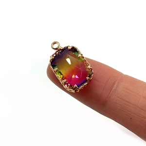 Faceted rectangular natural stone pendant with gold base held on a fingertip