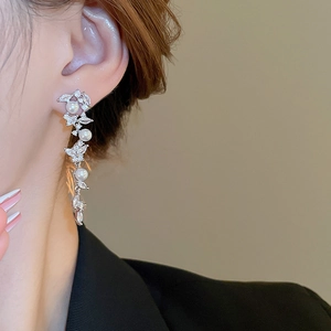 Detail of silver long tassel earrings with white pearls and zircons on female ear