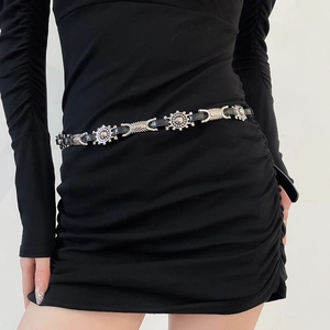 Detail of a thin black leather waist belt with vintage sun pattern silver metal carvings