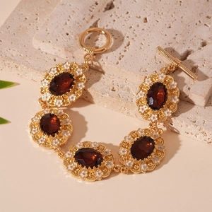 Close-up of vintage gold bracelet with red oval gems and small white flower details