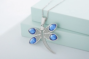 Close-up of dragonfly pendant with faceted blue crystal wings on silver chain