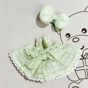 Close-up of light green plaid doll dress with white lace trim and matching bow hairpin