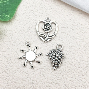 Close-up of alloy rose, sun and grape charms for DIY jewelry making in silver finish