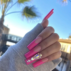 Macro view of long square French nails with pink tips and iridescent rhinestone accents