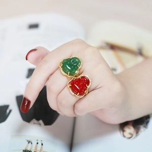 Detail of gold Buddha rings with green and red gemstones and sparkling crystal pavé