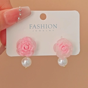 Detail view of pink resin rose earrings with large white pearl drop on jewelry card