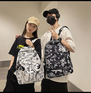 Street style backpacks with graffiti patterns shown on models in an industrial corridor