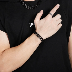 Close-up of men's black stainless steel Cuban link chain and silver ring on a model
