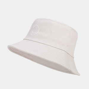 Détail du chapeau bob beige avec broderie sourire blanche et texture de tissu en coton