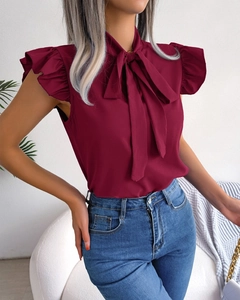 Detail of wine red sleeveless blouse with tie-neck collar and ruffle sleeve accents