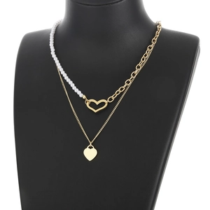 Detail of layered gold necklace featuring pearl splicing and hollow heart pendant