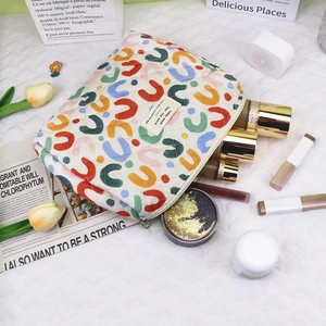 Detailed close-up of a quilted cotton floral makeup bag with cosmetics and metal zipper