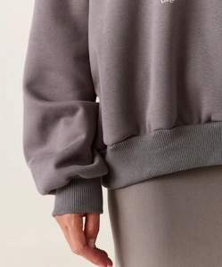 Detail der Rippbündchen und Elegant Schriftzug auf dunkelgrauem Baumwoll-Sweatshirt