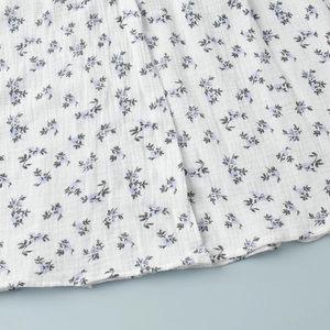 Detail of floral cotton dress hem showing blue flower print and ruffled texture