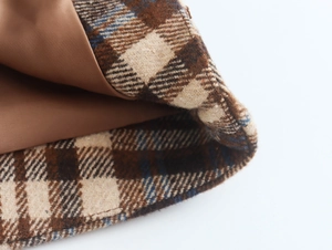 Detailed close-up of brown plaid wool blend fabric with smooth satin lining on the hem