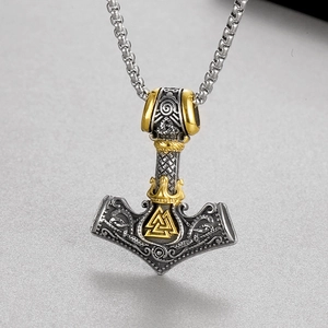 Macro view of Viking Mjolnir pendant with golden Valknut symbol on a steel chain
