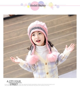 Dettaglio di un berretto in maglia rosa con paraorecchie e pompon per bambina e cardigan