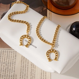 Gold horseshoe pendant necklace with crystals on a Cuban chain, displayed on white stand