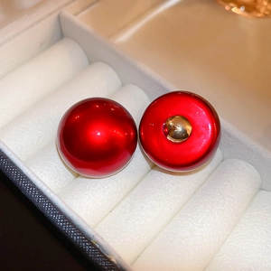 Detailed macro view of red round pearl studs in a white velvet box with gold metal back