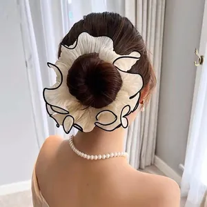 Detail of white oversized pleated scrunchie with black wave edge on a bun hairstyle
