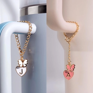 Detail of gold chain charms with enamel hearts and initial letters J and A for tumblers