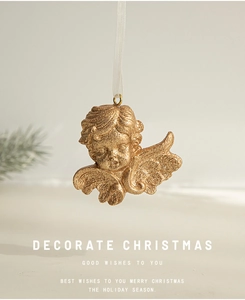 Detail of glittery gold angel Christmas ornament with white ribbon hanging on neutral wall