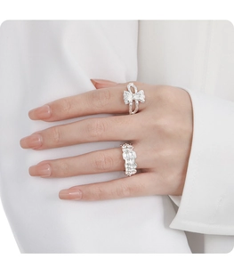 Detail of silver S925 bow and chain rings worn on hand with clean minimalist style