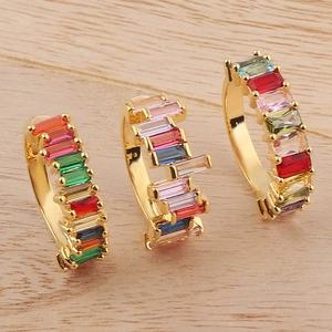 Detail of three gold rings with colorful rainbow crystals on a natural wood background