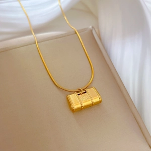 Detailed view of a gold-plated titanium Fu character locket pendant on a silk background