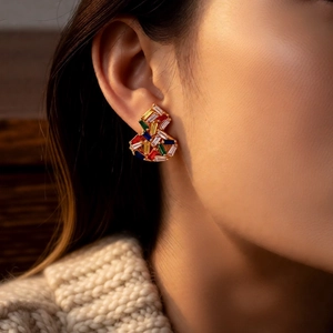 Primo piano di orecchini vintage placcati in oro con zirconi colorati su modella