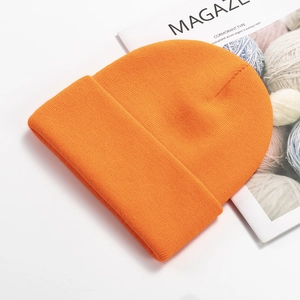 Detail shot of a bright orange knitted beanie on a fashion magazine background