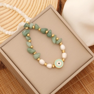 Macro shot of evil eye pendant bracelet with green stone beads and pearls on gift box