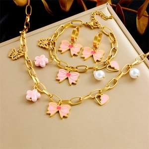 Detailed set of gold jewelry with pink bow, flower, and heart charms on a display
