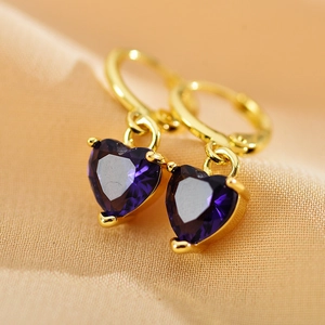 Golden hoop earrings featuring purple heart-shaped zircon pendants on beige fabric