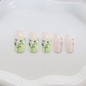 Unghie finte sfumate verde pastello con motivi floreali e foglie dipinti a mano