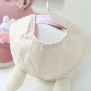 Detail of baby baseball cap back showing adjustable pink velcro strap and soft plush pom-poms