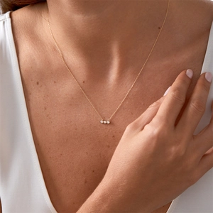 Détail d'un collier doré élégant avec trois pendentifs circulaires en oxyde de zirconium