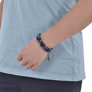 Detail of double-layer blue tiger eye and black stone beaded bracelet on a male wrist