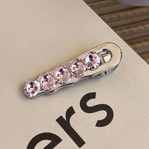 Detail of a rectangular silver hair clip with five sparkling pink rhinestones in a row