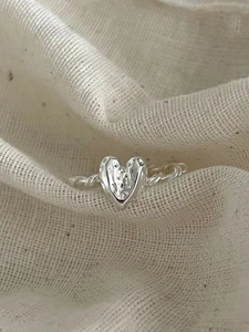 Textured 925 sterling silver heart ring with twisted rope band on beige linen fabric