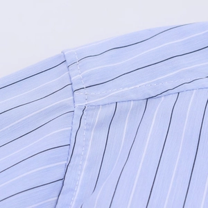 Detail shot of blue striped shirt showing precise double-stitch seam and cotton fabric texture