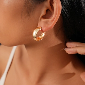 Close-up of gold-plated chunky hoop earring on model showing polished metallic finish
