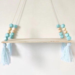 Detail of Nordic wooden swing shelf with turquoise octagonal beads and blue tassels
