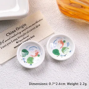 Macro shot of miniature 2.6cm porcelain dollhouse plates with red koi fish and lotus art