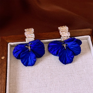 Macro detail of long drop earrings featuring square crystals and deep blue petals