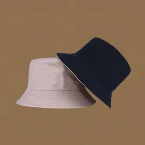 Detail of beige and navy reversible bucket hats showing canvas material and wide brim