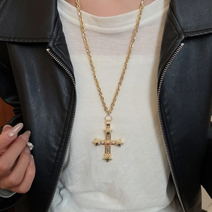 Golden cross pendant necklace with colorful gemstones worn on a black leather jacket