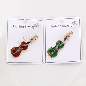 Detailed view of red and green enamel violin brooches with gold-plated metal finish