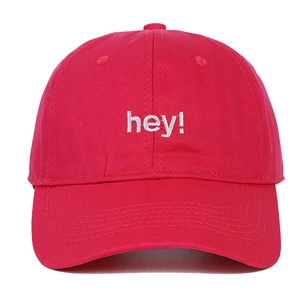 Détail de la broderie 'hey!' blanche sur une casquette de baseball en coton rouge foncé